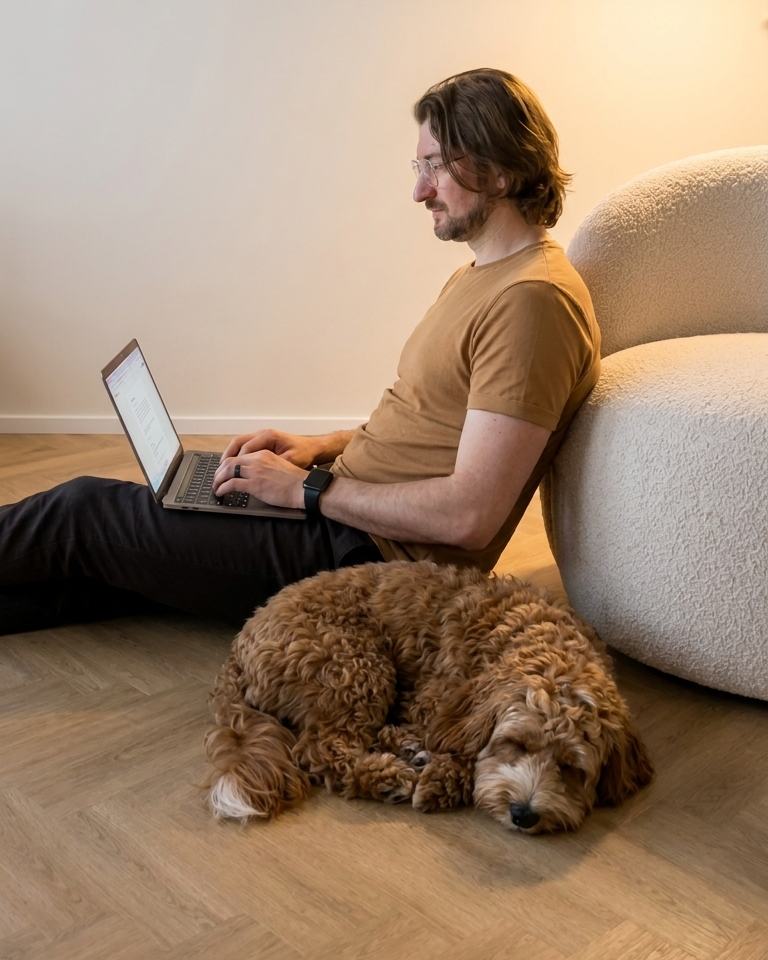 Damian pracuje przy laptopie, a obok odpoczywa jego pies Bursztyn.